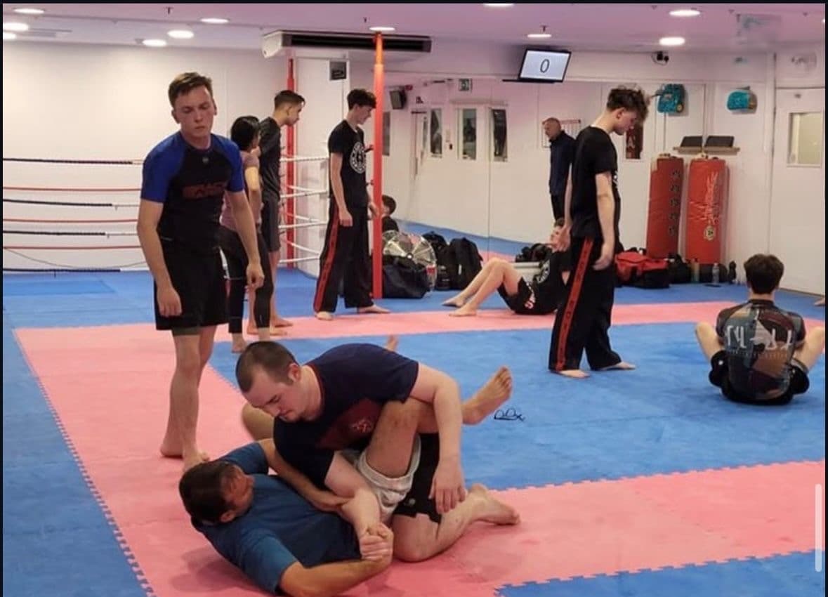 Students practising a grappling technique on the mats